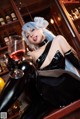 A woman in a black latex outfit holding a glass of wine.