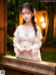 A woman in a white kimono standing on a wooden bench.