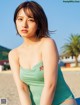 A woman in a green bathing suit sitting on a beach.