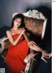 A woman in a red dress sitting on a chair.
