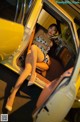A woman sitting in the driver's seat of a yellow car.