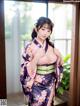 A woman in a purple kimono posing for a picture.