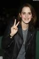 A woman in a black leather jacket making a peace sign.