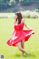 A woman in a red dress is walking in a field.