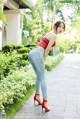 A woman in a red top and jeans posing for a picture.