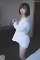 A woman in a white shirt is posing on a bed.