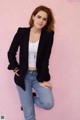 A woman in a black blazer and jeans posing for a picture.