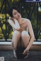 A woman sitting on a wooden bench with her legs crossed.