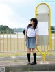 A woman in a school uniform standing next to a bus stop.